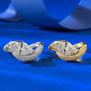Detail of silver and gold marquise cut rings with pavé diamonds on blue velvet