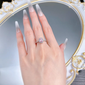 Macro detail of oval pink sapphire ring with halo diamond setting on woman's hand