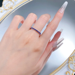 Close-up of a rose gold ring with pavé-set blue round-cut gemstones worn on a finger