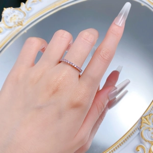 Close-up of a slim rose gold eternity ring with pink diamonds worn by a model