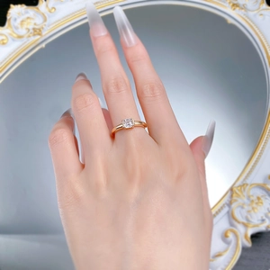 Close-up of a gold solitaire ring with square-cut clear stone worn by a model