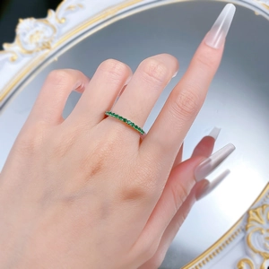 Detail shot of a slim S925 silver eternity ring featuring a row of vibrant green gemstones