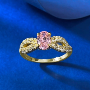 Macro shot of oval pink gemstone ring in gold setting with infinity diamond accents