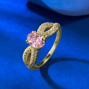 Detailed view of an oval pink gemstone ring with golden infinity band and diamonds