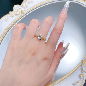 Detailed view of an oval-cut faux diamond ring in gold plating worn by a model