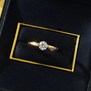 Macro shot of a classic round white diamond solitaire ring in a gold band and velvet box