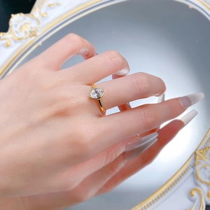 Macro detail of oval cut diamond ring in golden bezel setting on model finger
