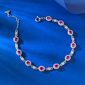 Bracelet en argent S925 avec rubis rouges ovales et halo de diamants sur tissu bleu