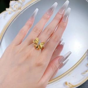 Close-up of S925 silver two-tone bow ring with gold pleats and white cubic zirconia on finger