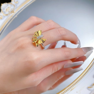 Close-up of dual-tone pleated bow ring with sparkling pavé zircons on woman's finger