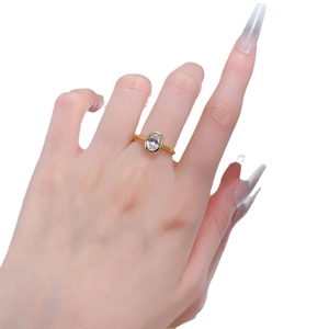Classic gold ring with oval cut white diamond in a bezel setting on female hand