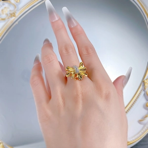 Detail of S925 silver plated gold pleated ribbon bow ring with inlaid white crystals