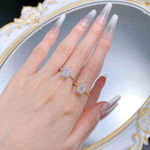 Detailed view of pear-cut rings with pavé set accents worn in silver and gold finishes