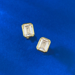 Macro shot of 6x8mm emerald cut clear stone bezel-set in gold stud earrings