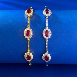 Macro detail of gold and silver rope bangles with red gemstone flower settings
