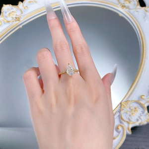 Macro shot of a pear-cut white stone ring with golden band and micro-pave details