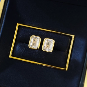 Elegant emerald cut yellow gold bezel earrings set in a navy blue velvet jewelry box