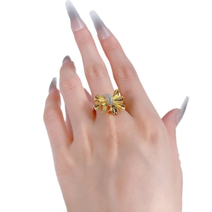Elegant gold pleated ribbon bow ring with sparkling zircon stones on female hand
