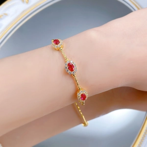 Détail du bracelet en argent S925 avec pierre rouge et chaîne torsadée dorée au poignet
