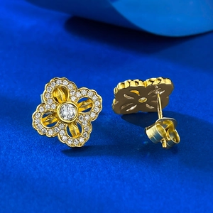 Detail of gold four-leaf clover earrings with sparkling pavé zircons and central stones