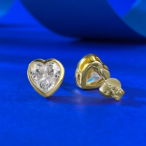 Détail de boucles d'oreilles cœur en pierre précieuse avec monture dorée et fermoirs papillon