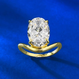 Macro shot of oval-cut crystal with four-prong setting and curved gold-plated ring band