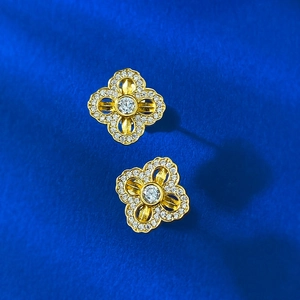 Golden S925 silver four-leaf clover earrings with white zircon on blue textured fabric