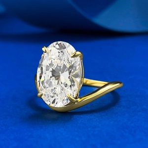 Macro side view of an oval cut clear gemstone set in a gold four-prong ring setting