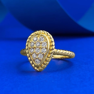 Dettaglio macro dell'anello a goccia dorato con pavé di pietre e bordo a corda