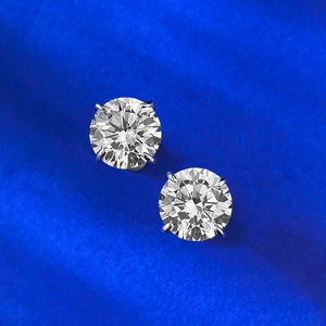 Macro shot of 1 carat round brilliant cut silver stud earrings with classic 4-prong setting