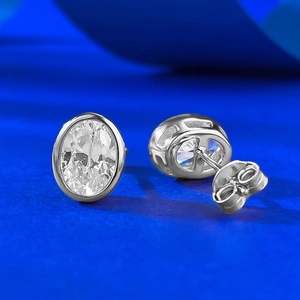 Detail of 6x8mm oval-cut bezel-set silver earrings with clear sparkling stones