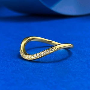 Macro shot of 18K gold wave ring with shimmering pavé diamond accents on blue background