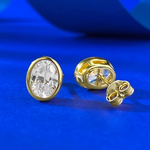 Macro view of oval cubic zirconia stud earrings with gold bezel setting and butterfly backs