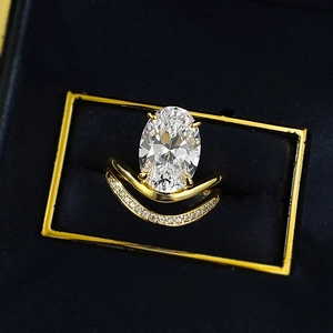 Elegant gold oval cut diamond ring with matching V-shaped pave band in a luxury box