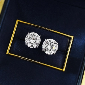 Close-up of brilliant-cut round silver stud earrings set in a navy velvet jewelry box