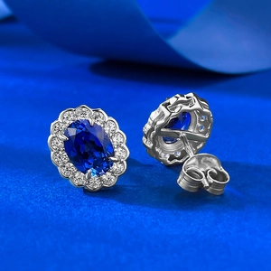 Close-up of royal blue oval sapphire earrings with diamond halo and silver push backs