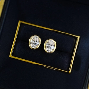 Elegant gold oval bezel set crystal stud earrings presented in a black jewelry box