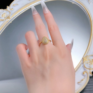Vista macro di un anello in argento dorato a forma di pera con pavé e fascia a treccia