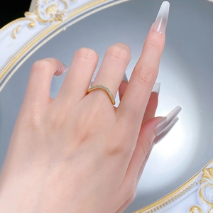Close-up of a gold curved band ring with sparkling white zircon inlays on hand