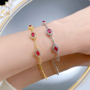 Detail of red gemstone bracelets in gold and silver with woven textured metal bands
