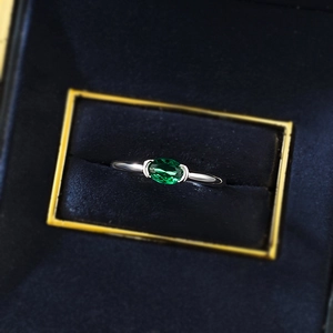 Vista macro di un anello con gemma ovale verde smeraldo e montatura in argento