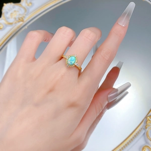 Macro shot of S925 gilded vintage ring with oval blue opal and side crystals