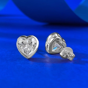 Detailed view of S925 silver heart stud earrings with sparkling stones on blue silk