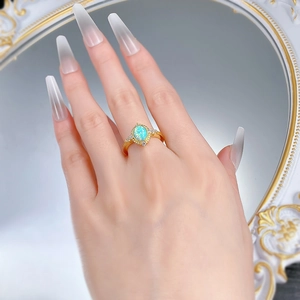 Close-up of vintage S925 gilded ring with oval blue opal and zircon pavé detailing
