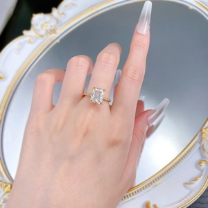 Close-up of radiant cut rectangle diamond ring on model hand with vintage gold mirror