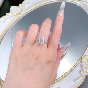 Macro view of a radiant cut diamond ring with pavé setting on a feminine hand