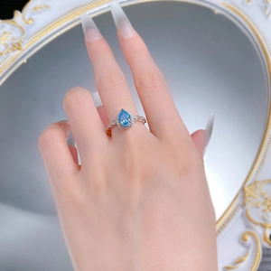 On-hand view of a vintage S925 silver ring with a pear-shaped blue gemstone and halo