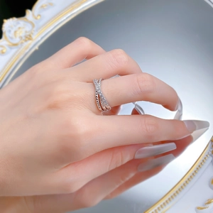 Detail view of silver S925 cross ring with paved zircons and quilted texture on finger