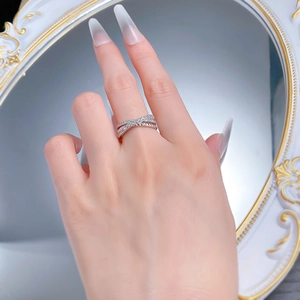 Close-up of a silver crossover ring with pavé cubic zirconia set against a mirror