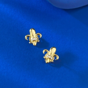 Detail of golden fleur-de-lis earrings with rhinestones on dark blue velvet